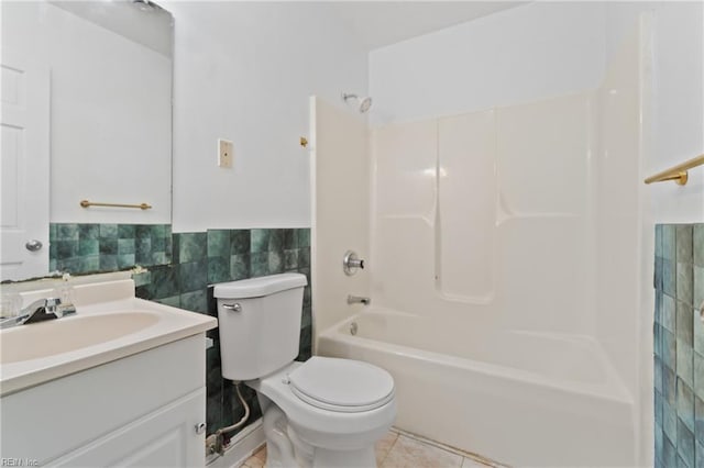 full bathroom featuring toilet, tile patterned floors, vanity, tile walls, and shower / tub combination