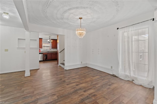 unfurnished dining area with dark wood-type flooring, a notable chandelier, and sink