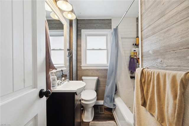 full bathroom with toilet, vanity, wood walls, and shower / tub combo with curtain