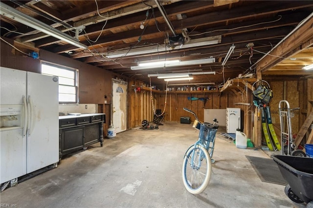 basement featuring white refrigerator with ice dispenser and a workshop area