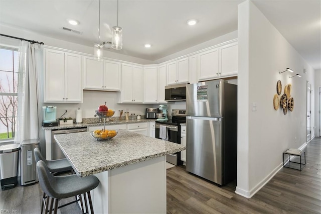 kitchen featuring stainless steel appliances, white cabinetry, a kitchen island, and pendant lighting