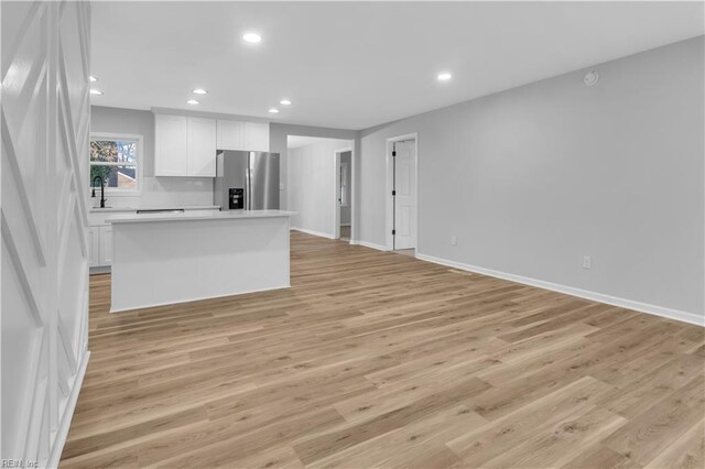 kitchen featuring white cabinetry, stainless steel fridge with ice dispenser, a center island, and light hardwood / wood-style flooring