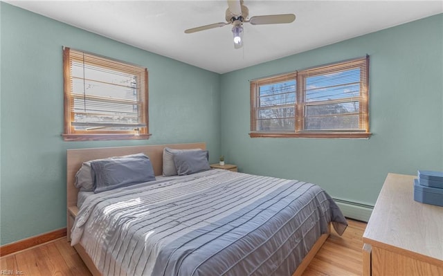 bedroom featuring baseboard heating, ceiling fan, and light hardwood / wood-style flooring