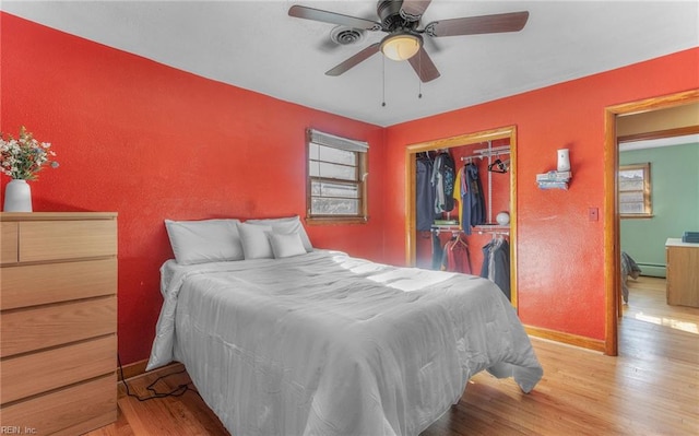 bedroom with a baseboard radiator, ceiling fan, a closet, and light hardwood / wood-style flooring