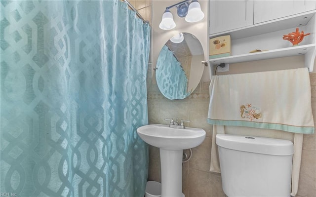 bathroom featuring toilet, a shower with curtain, and tile walls