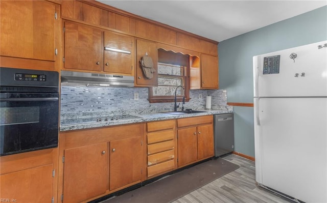 kitchen with light stone counters, black appliances, light wood-type flooring, backsplash, and sink