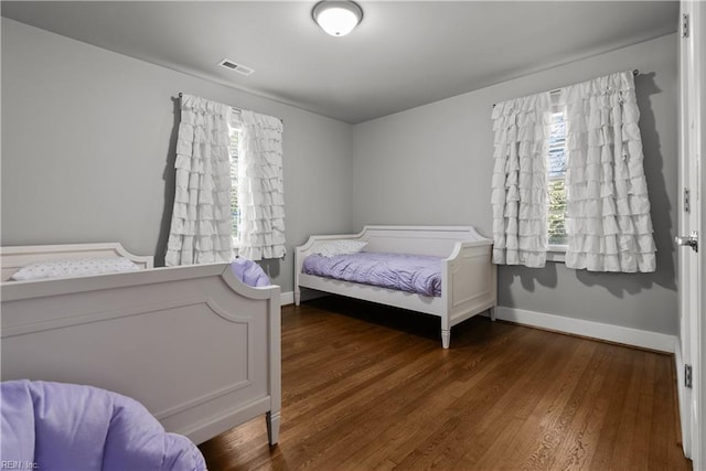 bedroom featuring dark hardwood / wood-style flooring and multiple windows