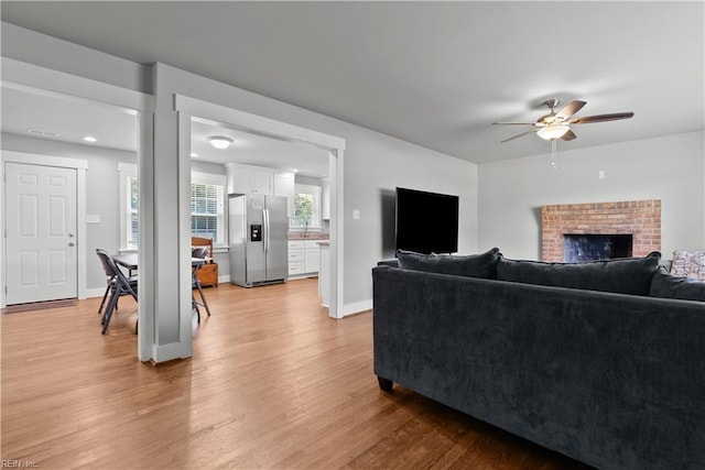 living room with a fireplace, ceiling fan, and hardwood / wood-style floors