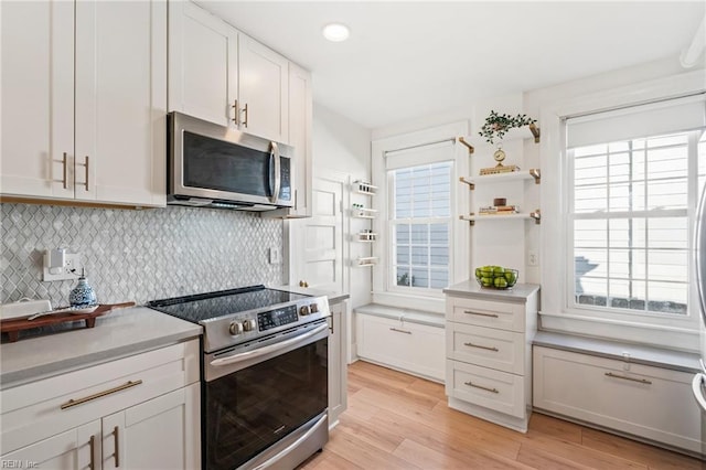 kitchen featuring white cabinets, decorative backsplash, light hardwood / wood-style floors, and appliances with stainless steel finishes