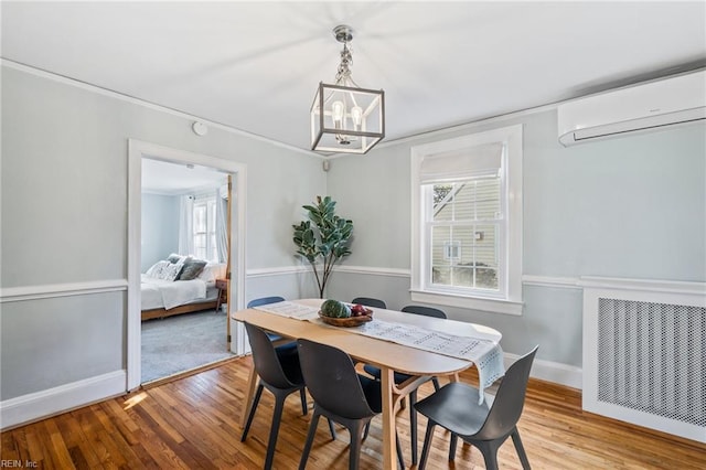 dining room featuring an AC wall unit, a chandelier, and light hardwood / wood-style floors