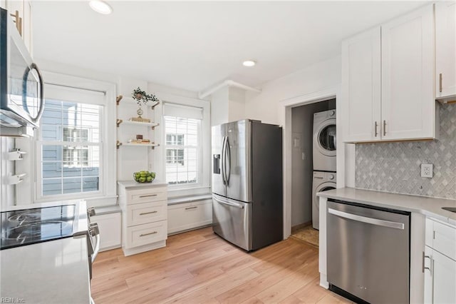 kitchen with white cabinets, appliances with stainless steel finishes, and stacked washer / dryer