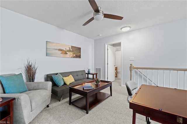 carpeted living room with ceiling fan and a textured ceiling