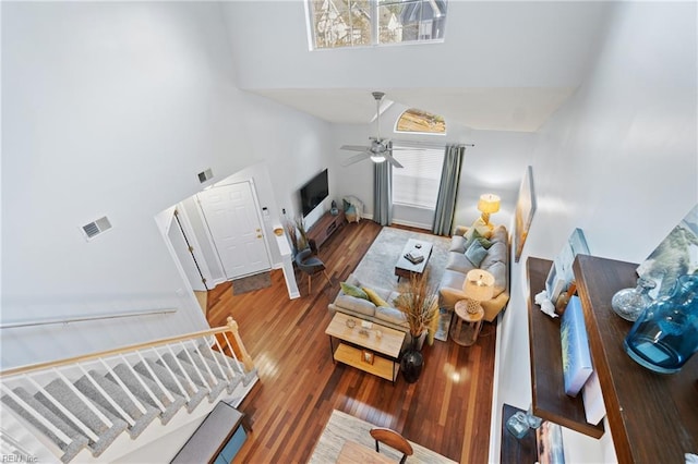 living room with ceiling fan, a towering ceiling, and wood-type flooring