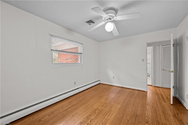 spare room with ceiling fan, baseboard heating, and light hardwood / wood-style floors