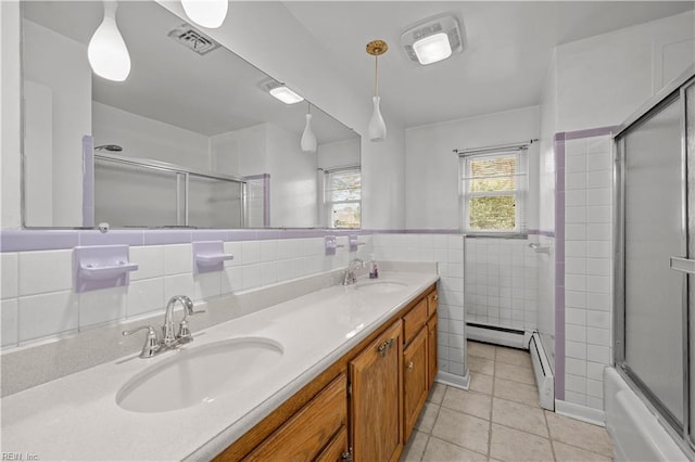 bathroom featuring vanity, tile patterned flooring, tile walls, combined bath / shower with glass door, and baseboard heating