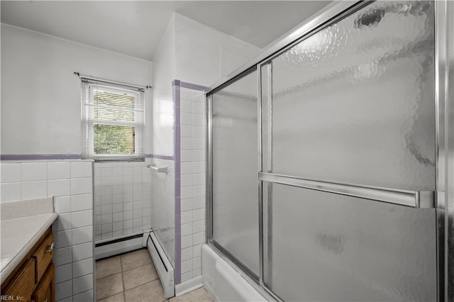 bathroom featuring combined bath / shower with glass door, a baseboard heating unit, tile walls, tile patterned floors, and vanity