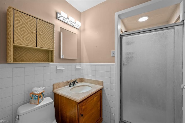 bathroom with walk in shower, vanity, tile walls, and toilet