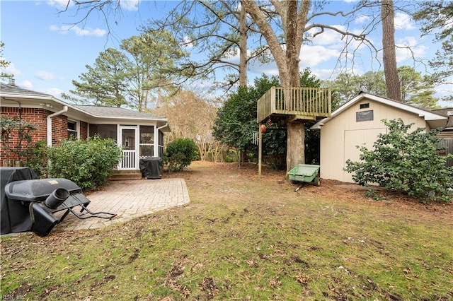 view of yard with a shed, a patio area, and a sunroom