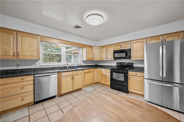 kitchen with black appliances, sink, light tile patterned floors, light brown cabinetry, and dark stone counters