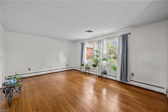 empty room with wood-type flooring and a baseboard radiator