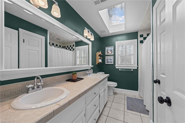 bathroom featuring a skylight, vanity, tile patterned floors, and toilet