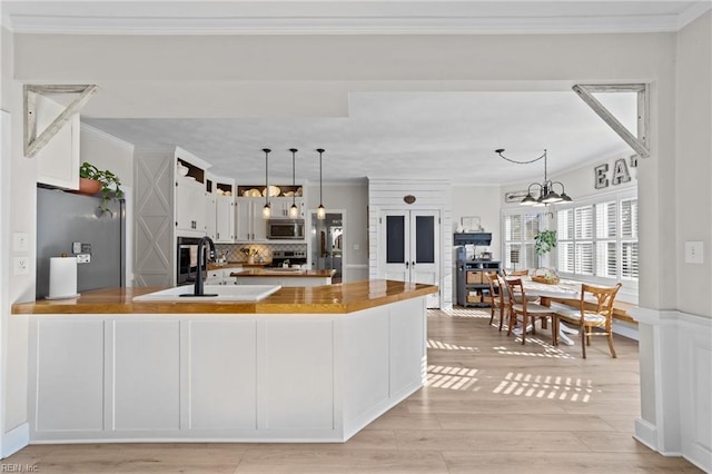 kitchen with a chandelier, stainless steel appliances, hanging light fixtures, sink, and backsplash