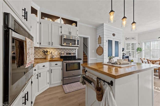 kitchen featuring stainless steel appliances, decorative backsplash, white cabinetry, decorative light fixtures, and butcher block counters