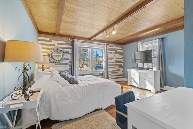 bedroom featuring wood ceiling, wood walls, rail lighting, light wood-type flooring, and beam ceiling