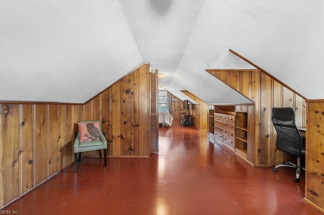 interior space featuring a textured ceiling, vaulted ceiling, and wood walls