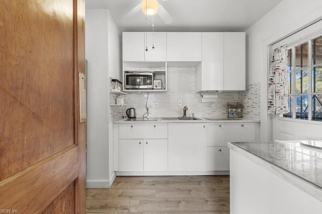 kitchen featuring sink, white cabinetry, ceiling fan, light hardwood / wood-style flooring, and backsplash