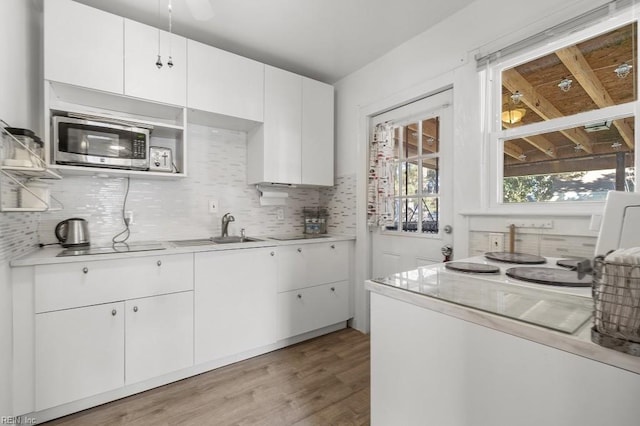 kitchen with sink, white cabinetry, decorative backsplash, and wood-type flooring