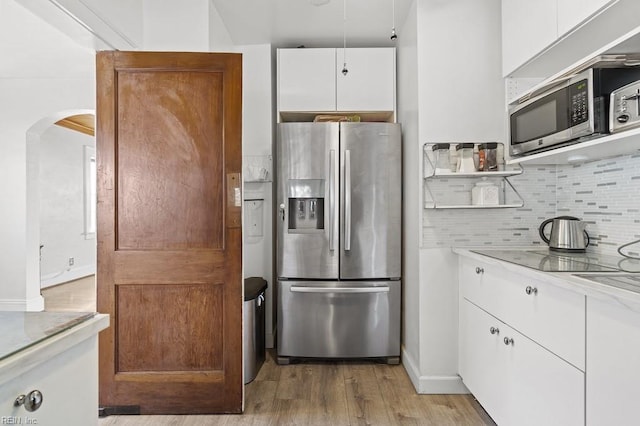 kitchen featuring light stone countertops, stainless steel appliances, light wood-type flooring, backsplash, and white cabinets