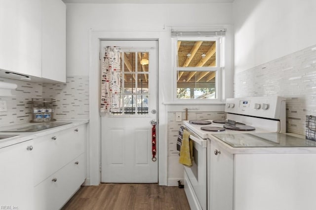 kitchen with white electric range, dark hardwood / wood-style floors, tasteful backsplash, and white cabinetry