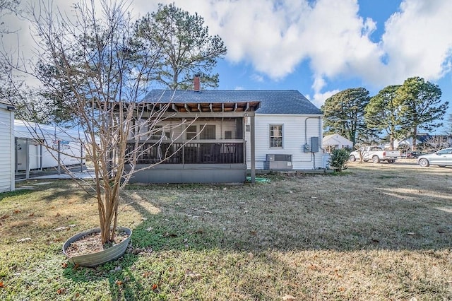 back of house with a sunroom and a lawn