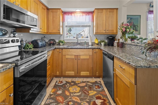 kitchen featuring appliances with stainless steel finishes, stone countertops, plenty of natural light, and sink