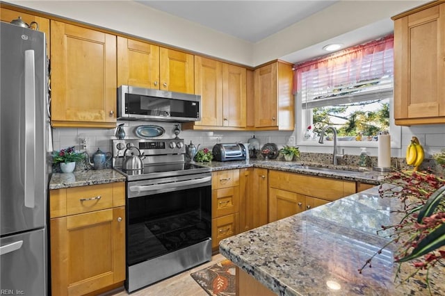 kitchen featuring appliances with stainless steel finishes, decorative backsplash, sink, and light stone countertops