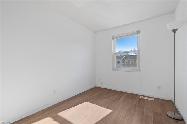 empty room with visible vents, baseboards, and wood finished floors