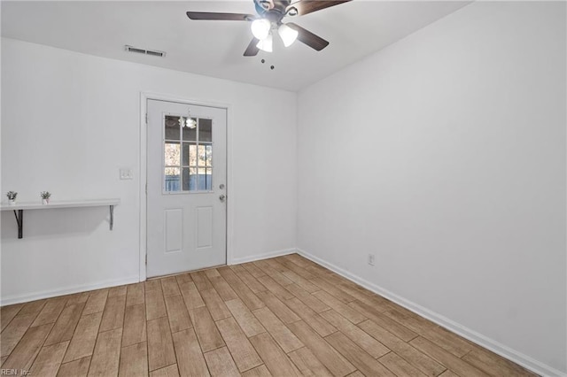 unfurnished room with ceiling fan, visible vents, baseboards, and wood finished floors