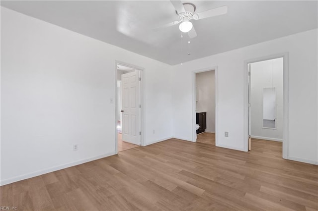 unfurnished bedroom with a walk in closet, baseboards, light wood finished floors, and connected bathroom