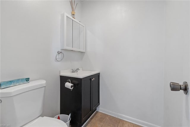 half bathroom featuring toilet, vanity, and baseboards