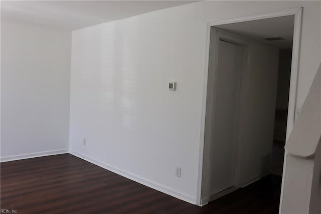 spare room featuring visible vents, baseboards, and dark wood finished floors