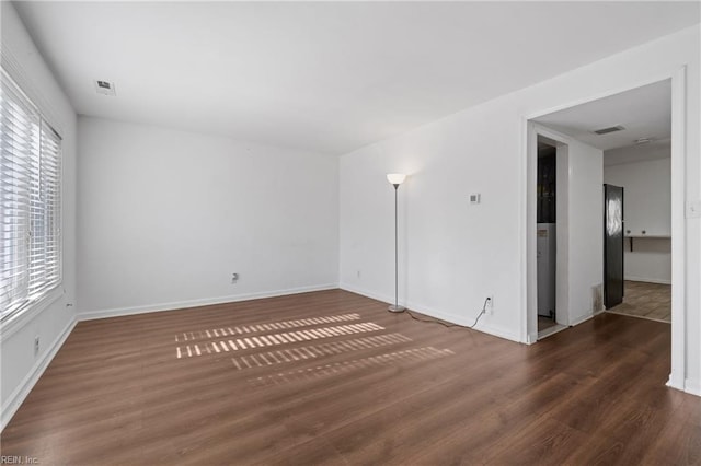 spare room featuring visible vents, wood finished floors, and baseboards