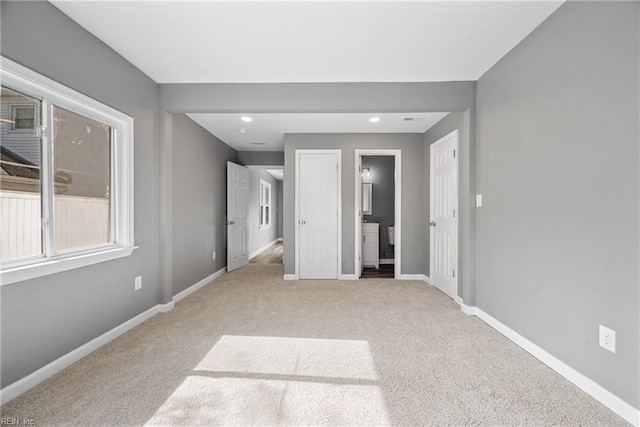 unfurnished bedroom featuring ensuite bathroom and light carpet