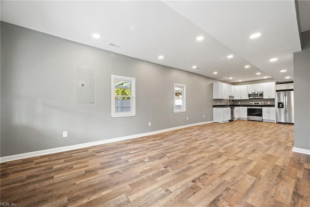 unfurnished living room with electric panel and light hardwood / wood-style flooring