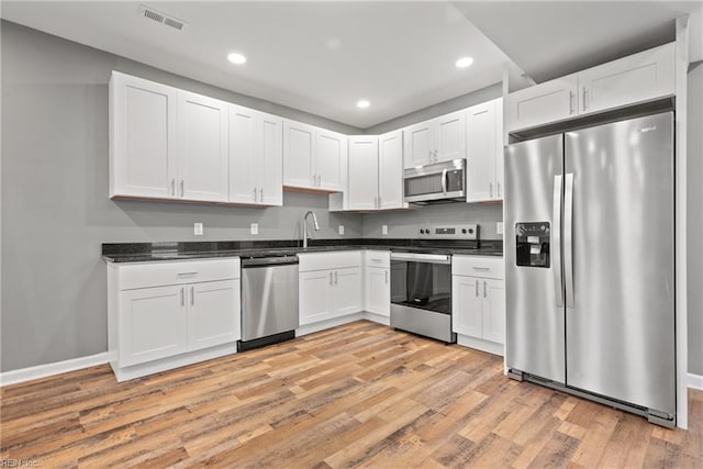 kitchen with sink, white cabinets, light hardwood / wood-style floors, and appliances with stainless steel finishes