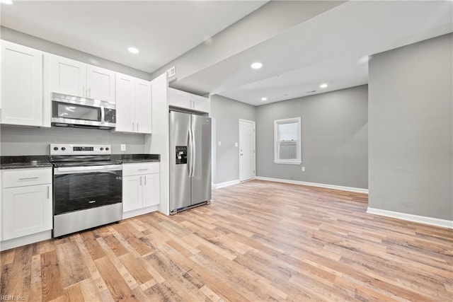 kitchen with stainless steel appliances, white cabinets, and light wood-type flooring