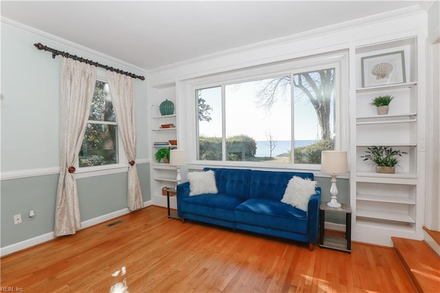 living area featuring a healthy amount of sunlight, crown molding, and wood-type flooring