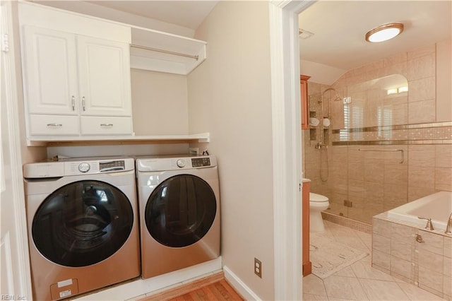 washroom featuring cabinets, light tile patterned floors, and washer and clothes dryer