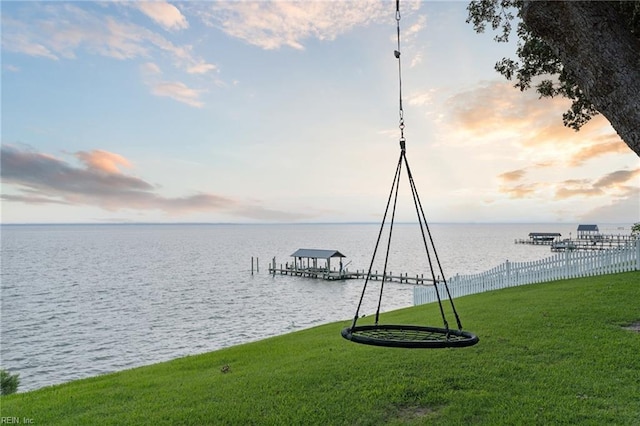 view of dock featuring a lawn and a water view