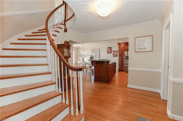 staircase with a notable chandelier, crown molding, and hardwood / wood-style flooring